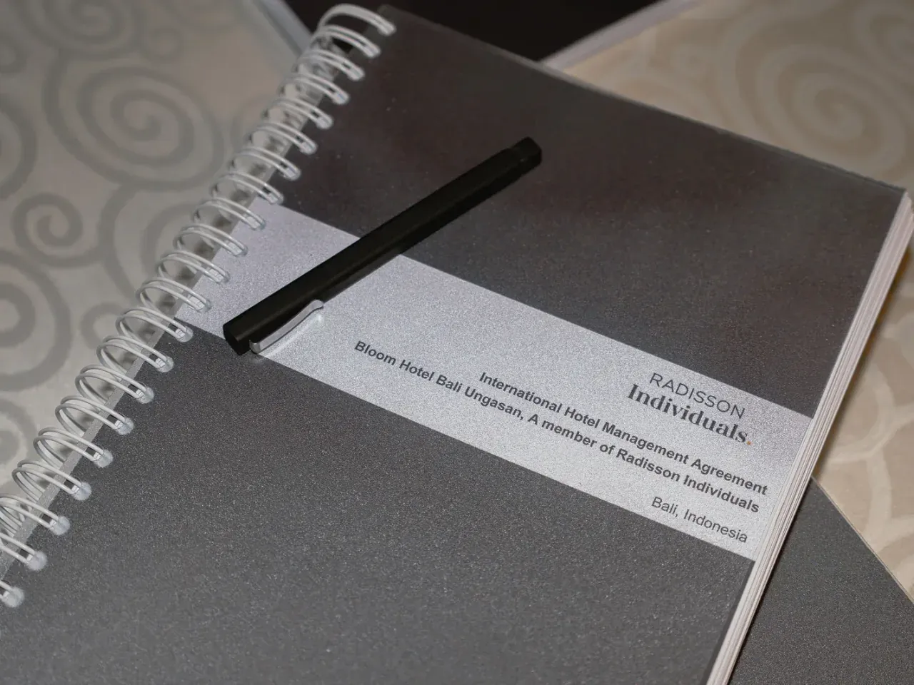 Bound hotel management agreement for Bloom, BY Radisson Individuals, with a pen resting on the cover