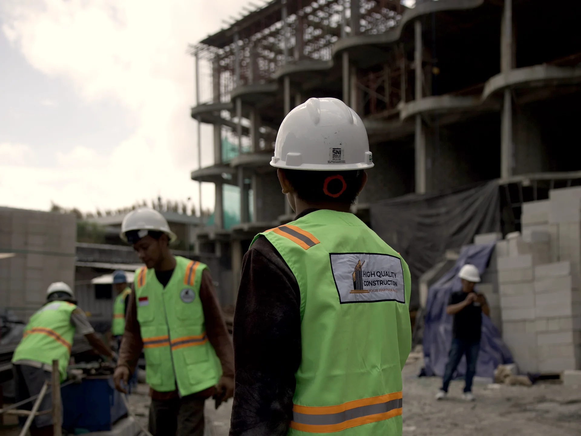 HQC builder in front of the structural frame on a Bali site